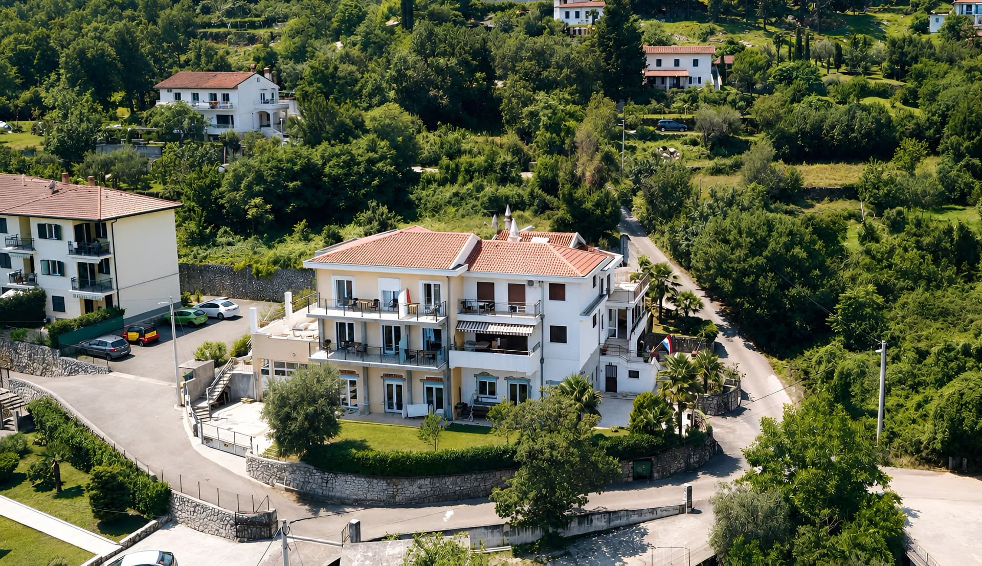 Villa Kubo from above — a white house with a terracotta roof on the green hillside over Lovran